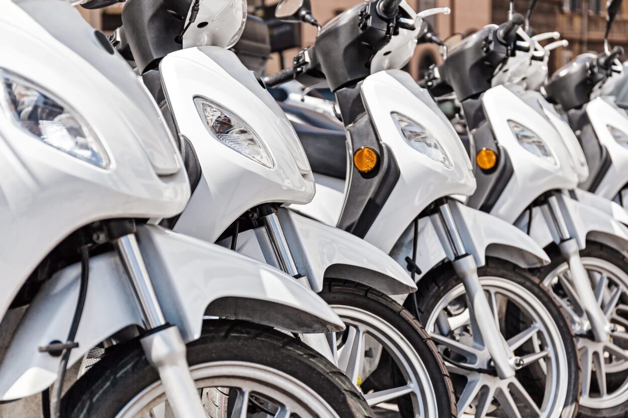 Series of white scooter parked in a row in the city.